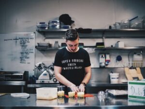 Osoba przygotowująca posiłek w profesjonalnej kuchni w restauracji. Profesjonalne urządzenia kuchenne.